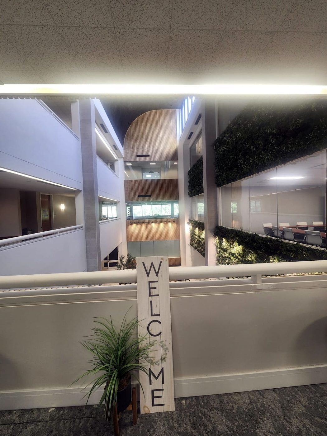 View across a commercial office atrium with green walls and linear lighting