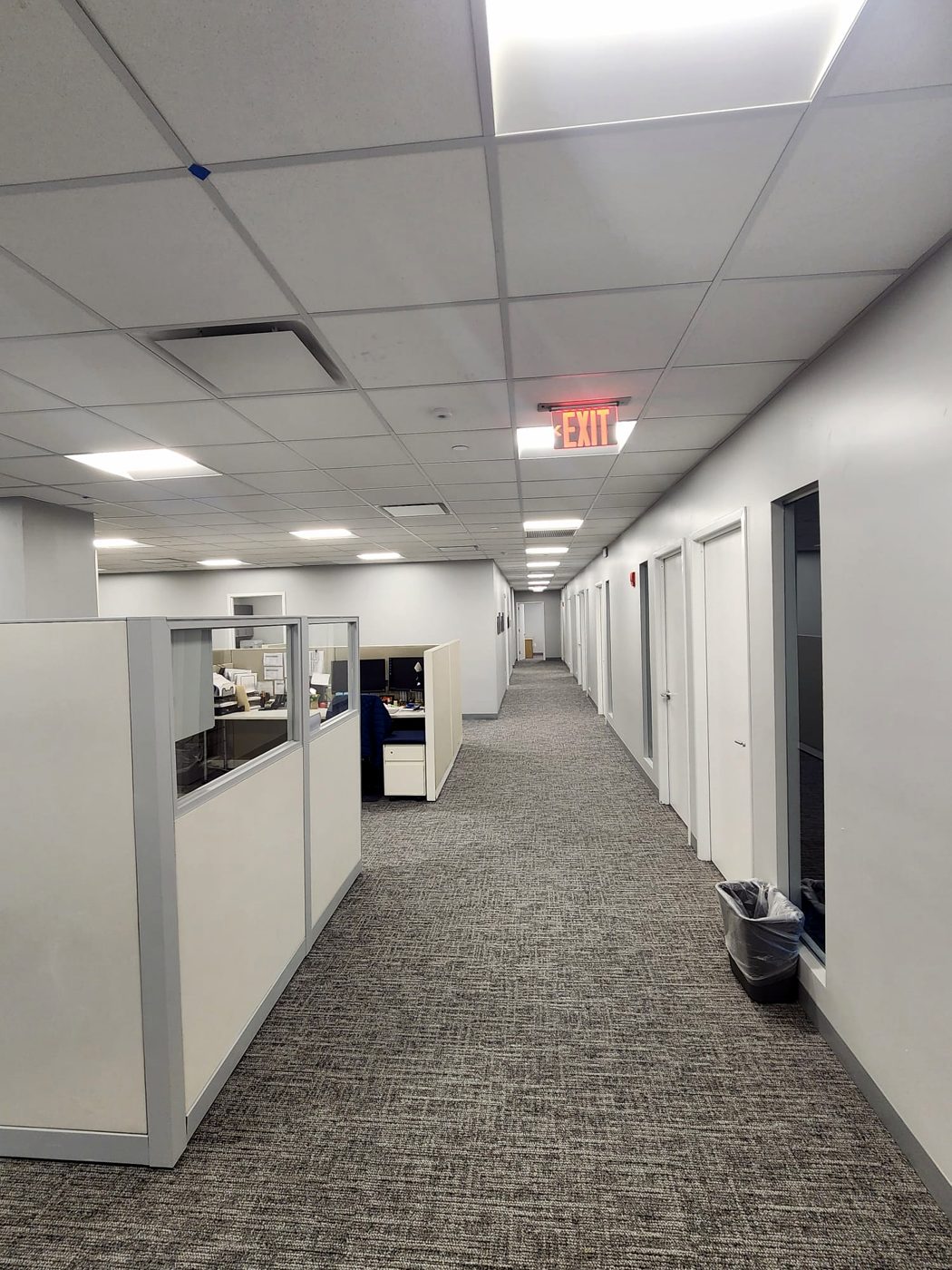 Finished office corridor with cubicles and exit signage