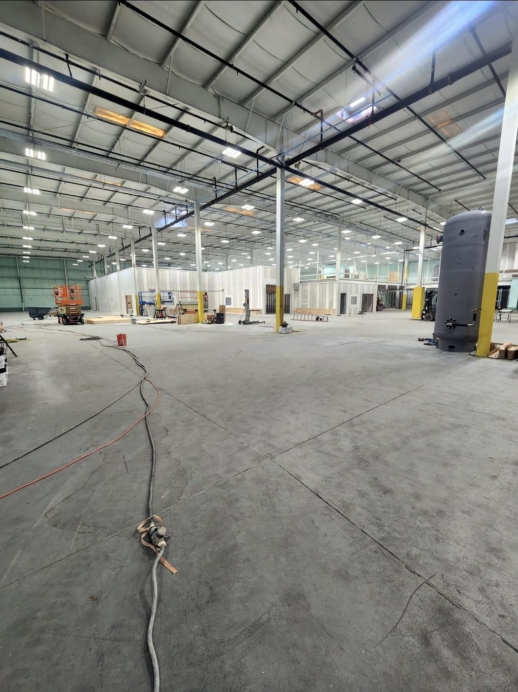 Large warehouse interior during build-out with cables and a scissor lift